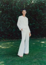 Pantalón blanco de corte recto y largo, con forro interior, tejido fluido, dos bolsillos laterales y cierre oculto de botón, gancho y cremallera.