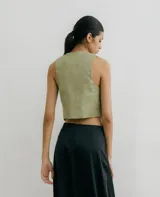 Chaleco corto color verde claro, confeccionado en lino, con cuello en V y cierre frontal con tres botones.