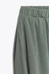 Pantalón bombacho color marrón de felpa de algodón, con cintura elástica, tiro alto, bolsillos laterales y puños elásticos en los tobillos.