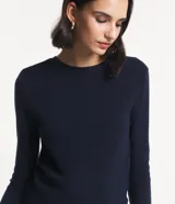 Blusa de punto rosa con textura acanalada, cuello redondo y mangas largas.