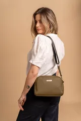 Bandolera pequeña de textura símil cuero color caramelo/marrón, con dos compartimentos principales con cierre. Correa ancha ajustable de tela negra con inscripción en relieve.