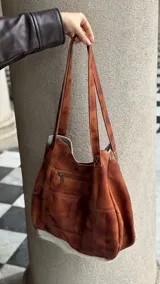 Bolso tipo tote de cuero con pelo de vaca color marrón y blanco. Tiene doble asa de cuero marrón y bolsillo interno.