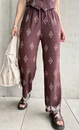 Pantalón marrón con estampado de rombos blancos y cintura elastizada.