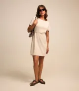 Vestido corto color crema, de corte recto, con cuello redondo y mangas cortas. Incluye cinturón fino con hebilla.