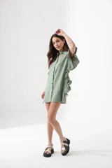 Camisa larga verde con botones frontales y detalles de volantes en las mangas, de estilo atemporal.