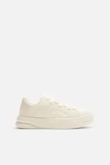 Zapatillas bajas color crema con cordones y suela gruesa. Presenta un diseño con paneles de cuero sintético liso y con textura de piel de serpiente.