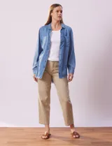 Camisa celeste de tencel marca Hester & Orchand, con cuello con solapa, escote en V y abertura central con botones. Tiene un bolsillo aplicado en la delantera y ruedo desflecado.