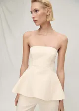 Top color crema con corte peplum, palabra de honor y cierre de cremallera en la parte posterior.