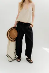 Pantalón negro de lino con tiro medio, pinzas frontales, pretina ancha en la espalda con cambio de color y vivo en contratono, cortes en la mitad de la pierna de la espalda, cierre frontal con botón y bolsillos delanteros.