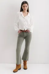 Pantalón jean marrón acampanado con detalle desflecado en el bajo y tiro medio.