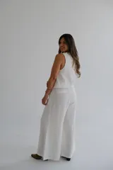 Pantalón palazzo color blanco hueso, de tiro alto y corte holgado. Confeccionado en lino.
