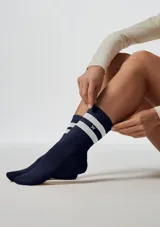 Medias deportivas de caña media, color azul marino, con dos franjas blancas horizontales en la parte superior y un pequeño logo bordado en blanco.