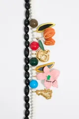 Collar doble con cuentas blancas y negras, con dijes colgantes de animales, flores y hojas en colores variados.