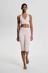 Top deportivo color rosa claro, de sujeción suave, confeccionado en tejido funcional con tecnología SoftMove™ y DryMove™. Tiene breteles finos cruzados en la espalda y copas forradas con relleno extraíble.