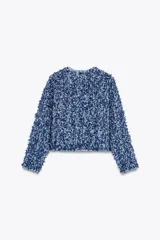 Chaqueta corta azul con tejido de punto entrelazado, cuello redondo, manga larga, bolsillos delanteros de plastrón y cierre frontal con botones dorados.