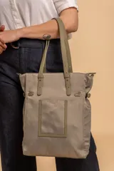 Cartera tipo tote bag color negro, con doble asa de mano y correa bandolera ajustable. Presenta un bolsillo rectangular en el frente.