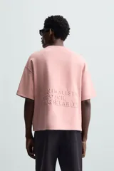 Camiseta color crema de corte recto, cuello redondo y manga corta. Estampado con texto en relieve en el frente.