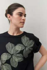 Remera blanca de manga corta con estampado floral en tonos dorados en el frente.