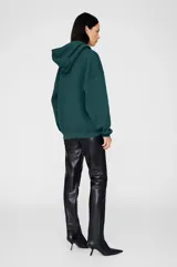 Hoodie oversize verde oscuro con capucha y estampado ANINE BING en el pecho, con bolsillo tipo canguro frontal.