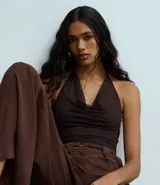 Body color marrón oscuro, de frente única, confeccionado en tul con escote drapeado (degagê) y espalda abierta. Tiene cierre en la entrepierna y forro.