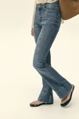 Pantalón de jean azul de tiro alto con nervio marcado delantero, bolsillos delanteros y traseros, bajo acampanado y cierre frontal con cremallera y botón.