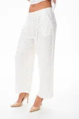 Pantalón palazzo blanco con estampado de hojas doradas, con bolsillos laterales y corte holgado.