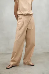 Pantalón de vestir color beige, de corte ancho y cintura alta, con pinzas delanteras.