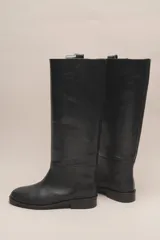 Bota alta de cuero color marrón, con caña recta y suela plana.