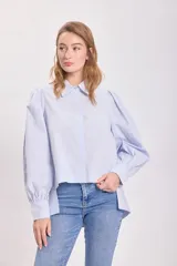 Camisa celeste con hombreras y mangas abullonadas.