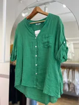 Camisa celeste de lino, con cuello mao, manga 3/4 con botón para sujetar, cierre frontal con botones y bolsillo de parche en el pecho.