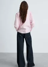 Camisa de mujer a rayas verticales rosas y blancas, de corte recto y manga larga con puños abotonados.