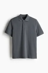 Remera polo gris de piqué de algodón, de manga corta, con cuello clásico, tapeta de botones, remate acanalado en cuello y mangas, bajo recto con aberturas laterales y corte estándar.