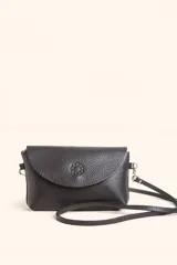 Cartera tipo bandolera de cuero negro con solapa frontal, cierre principal y detalle de logo grabado en el centro de la solapa. Incluye correa larga ajustable.