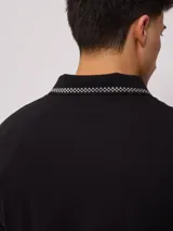 Remera polo negra de corte regular, con cuello y mangas con rayas en contraste blancas y logo bordado en el pecho.