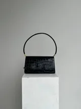 Cartera negra de hombro con textura tipo cocodrilo, doble compartimento interno, dije metálico con la letra B y cierre con broche imán.