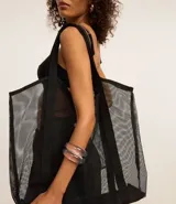 Bolso de playa mediano de tela de poliéster transparente color negro con ribetes y asas de tela negra.