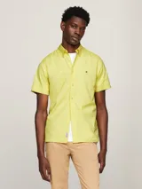 Camisa amarilla de manga corta con cuello abotonado y logo de Tommy Hilfiger bordado en el pecho.