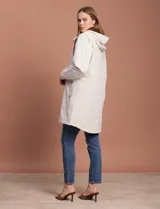Gabardina negra impermeable con capucha desmontable, cierre central con cremallera y botones a presión, bolsillos delanteros y forro interno.