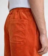 Short masculino de pana color naranja vibrante, con cintura elástica y cordón de ajuste blanco. Presenta bolsillos laterales y un corte recto.