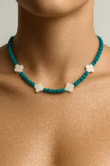 Gargantilla de cuentas de cristal color turquesa y dijes de trébol de cuatro hojas color blanco.