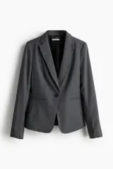 Blazer entallado gris con solapas de muesca y cierre de un botón. Tiene bolsillos ribeteados en el frente, botones decorativos en los puños y abertura en la parte posterior.