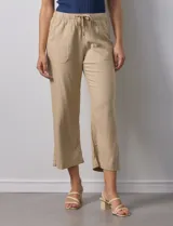 Pantalón color beige, marca Dash, de corte cropped y pretina trasera elastizada. Presenta bolsillos delanteros y traseros.