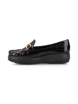 Mocasín de cuero charol negro con plataforma blanca y detalle de hebilla metálica plateada en el empeine.