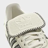 Championes Adidas Samba LT color crema con las tres tiras laterales negras con costuras en forma de equis. Suela de goma marrón.