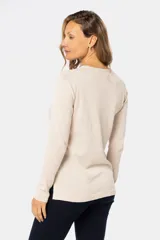 Buzo color beige de tejido de punto con bordado de pequeñas flores blancas.