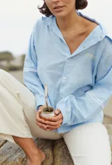 Camisa celeste de lino con botones y bordado de estrellas doradas en el pecho.