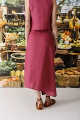 Conjunto de top sin mangas y falda midi color fucsia, con botones dorados. La falda presenta una abertura lateral.