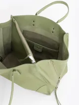 Bolso tote pequeño de cuero vacuno negro, con cierres funcionales en los laterales para mayor apertura y espacio. Incluye bolsillo cruzado interno y tag con aplique metálico.