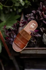 Sandalias de cuero negras con diseño de tiras cruzadas y detalle de elástico en el talón.