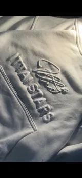 Buzo hoodie color crema con bolsillo tipo canguro y logo de la marca bordado en el frente.